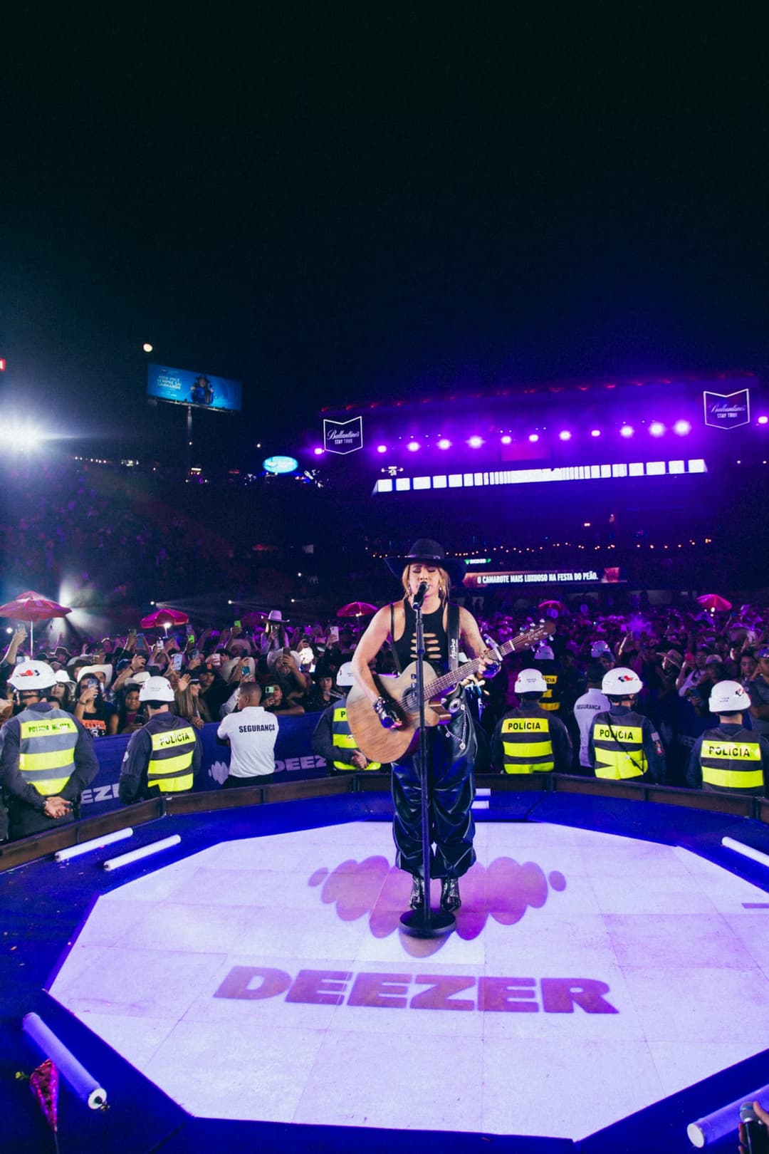 Country artist performing in front of a crowd of Deezer fans on a stage branded for Deezer